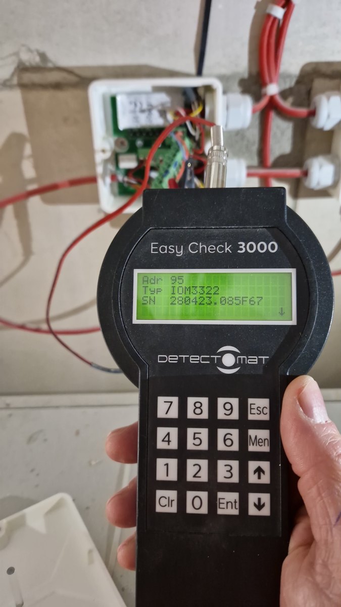 Handmessgerät am geöffneten Koppelmodul einer Ringleitung; das Display zeigt Adresse, Typ und Seriennummer des Teilnehmers