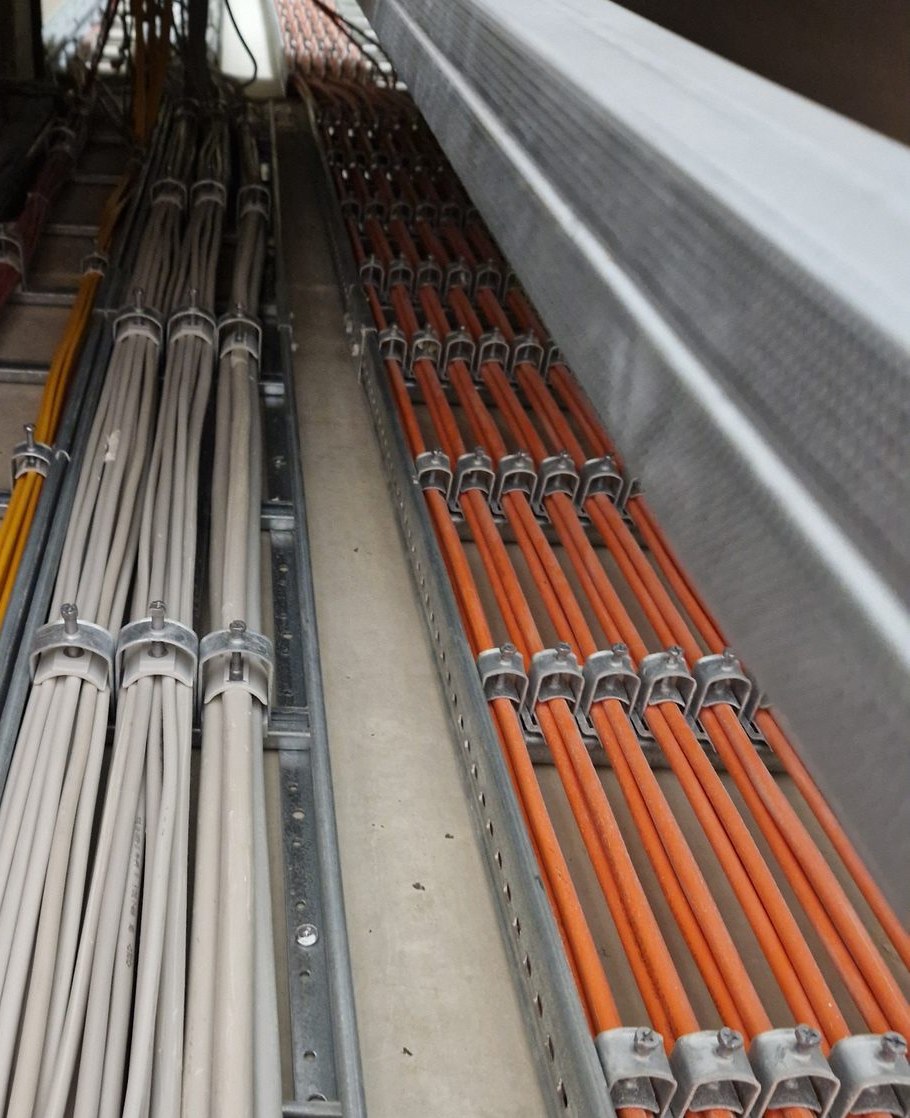 Kabeltrassen mit getrennten Lagen: Datenleitungen, Energie und Meldekabel, jede in Schellen geführt