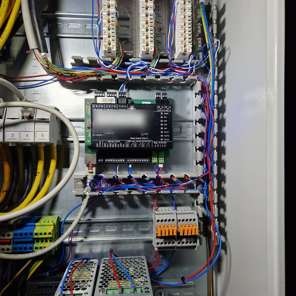 Geöffneter Etagenverteiler: Türcontroller auf der Hutschiene, Patchfelder, Reihenklemmen und Netzteile, alle Adern sauber im Kabelkanal geführt